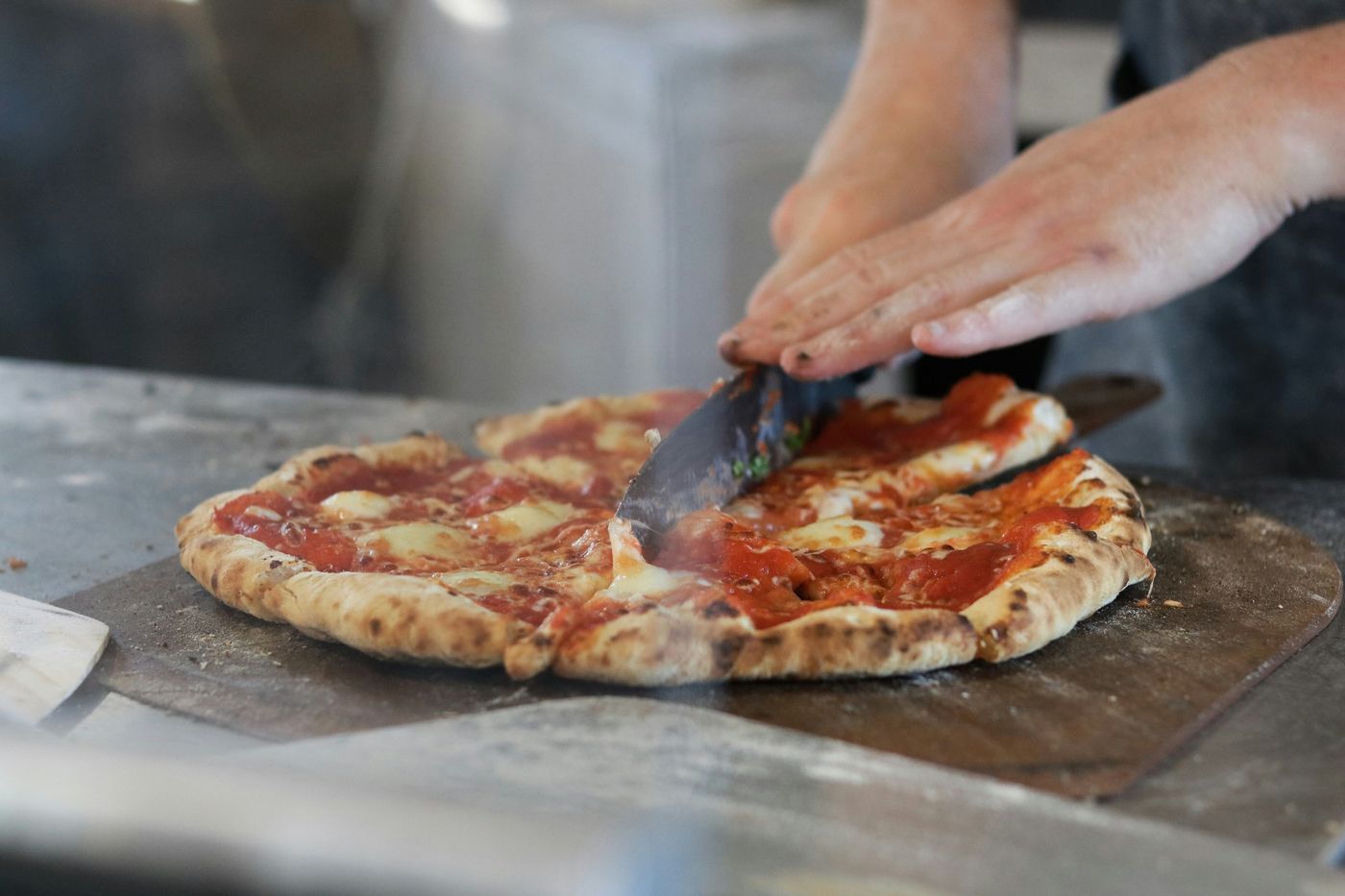 Chef slicing a round Margherita pizza