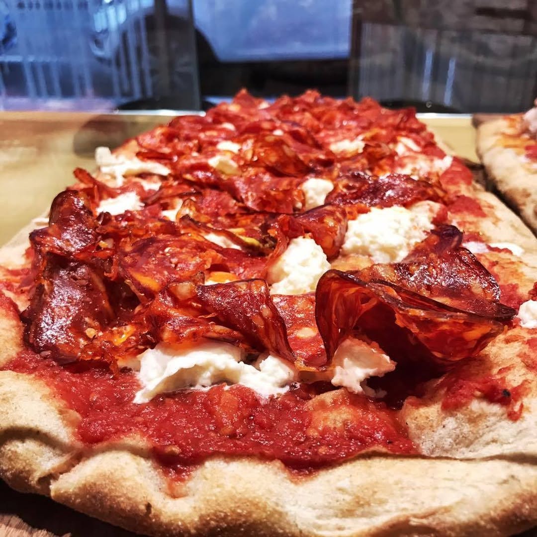 Rectangular tray pizza topped with spicy salame and mozzarella