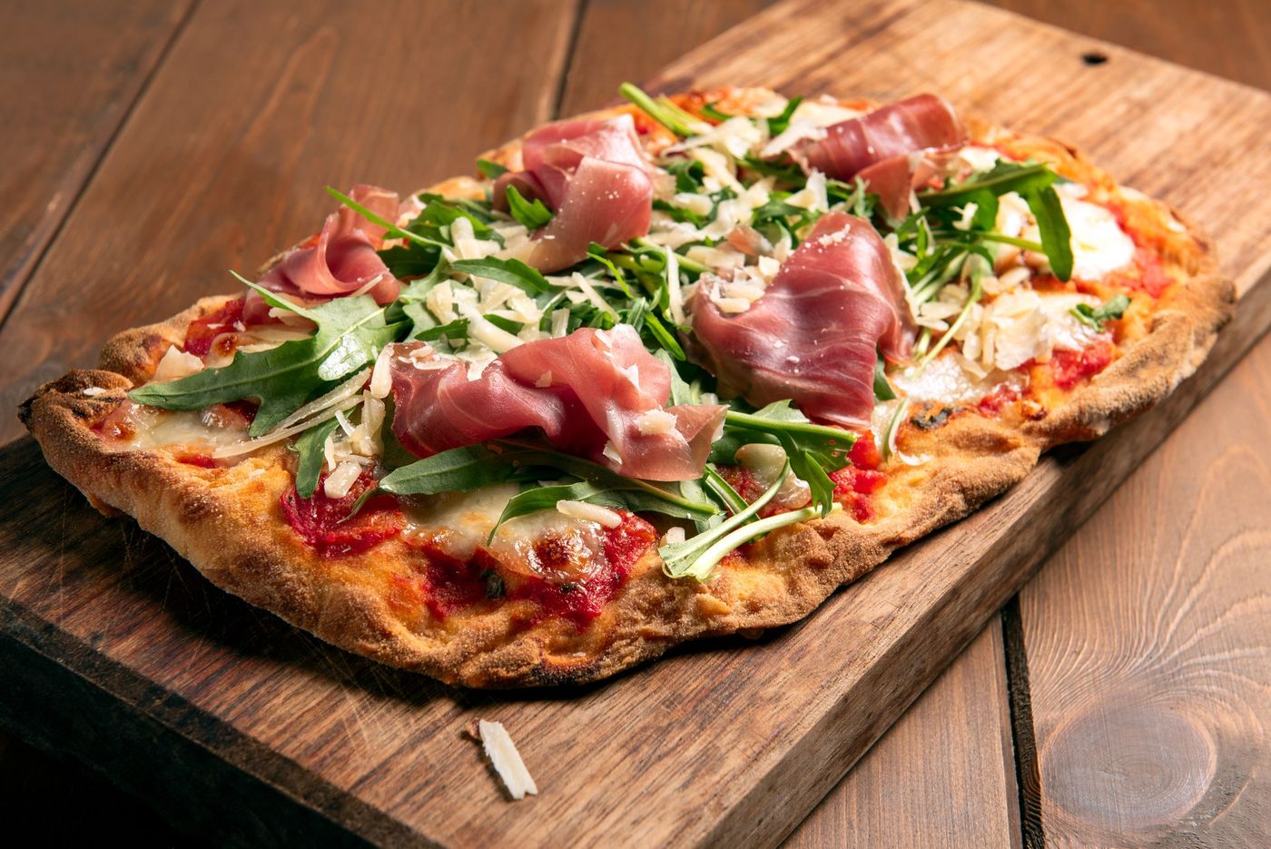 Pinsa ovale topped with prosciutto crudo, rocket and shaved parmesan
