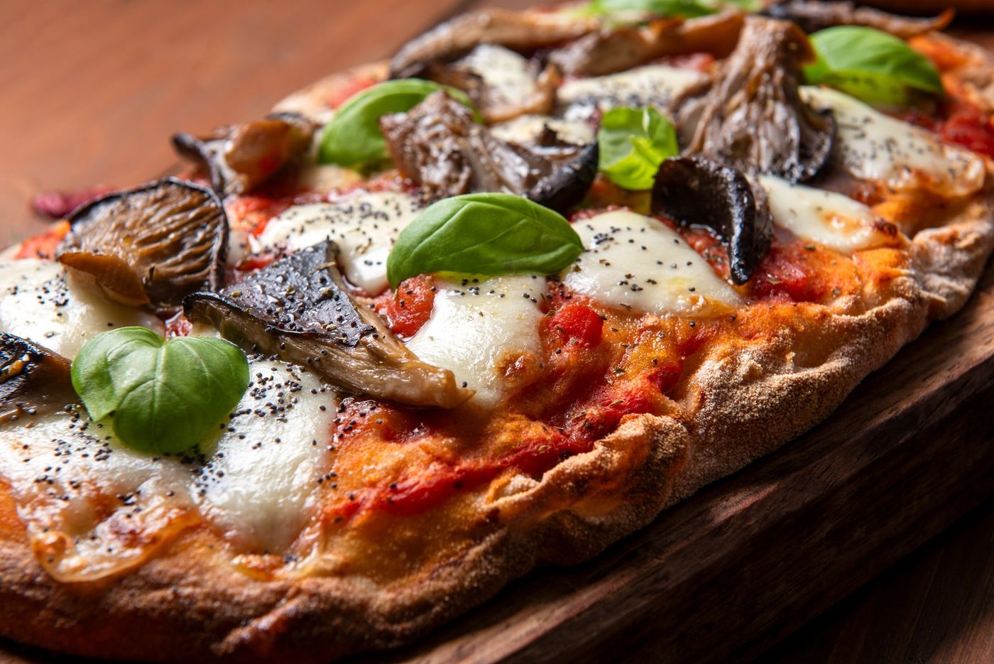 Pinsa ovale topped with mushrooms, mozzarella and basil